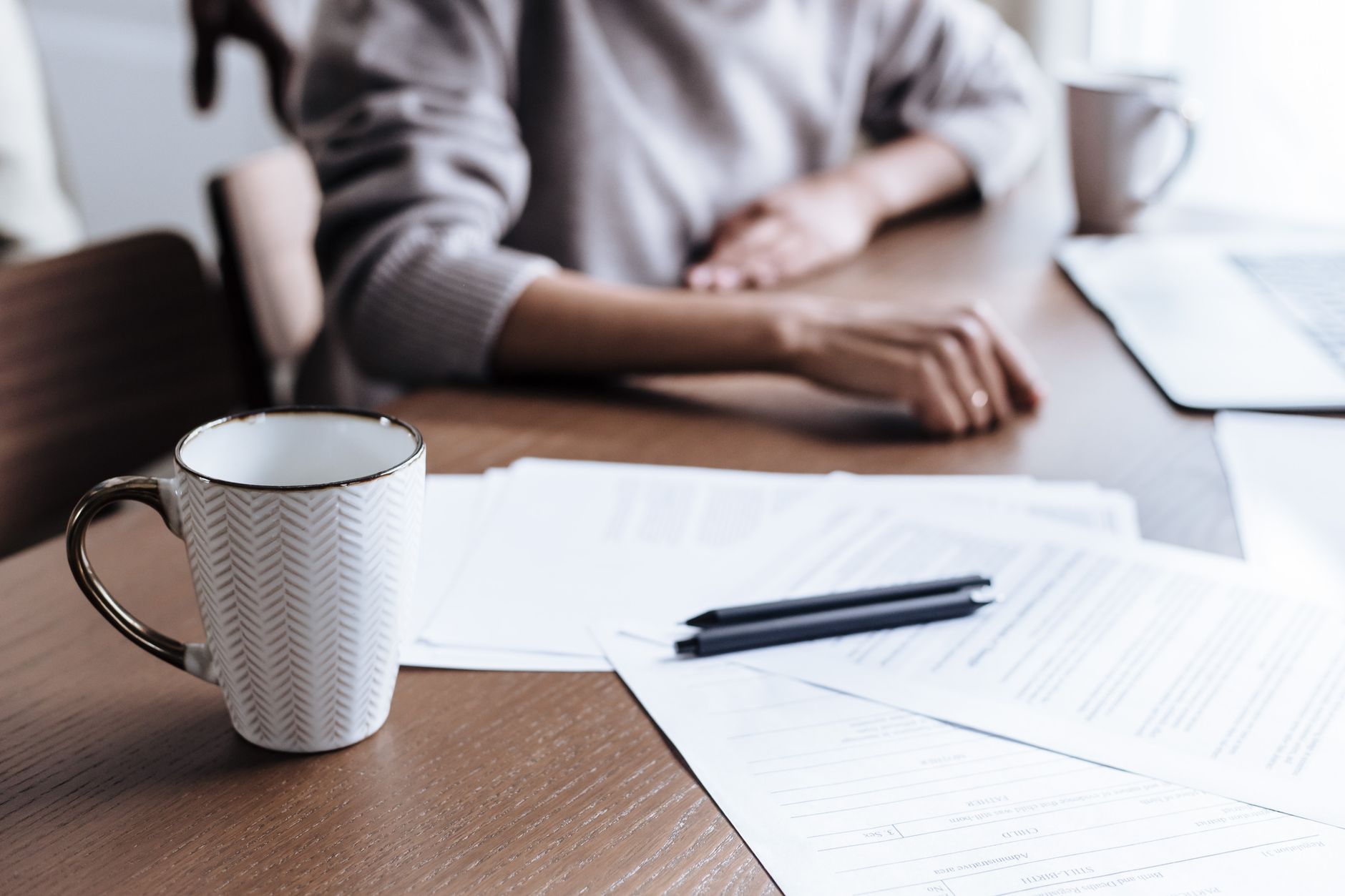 Documents, notes and a coffee cup on a warm wooden desk
