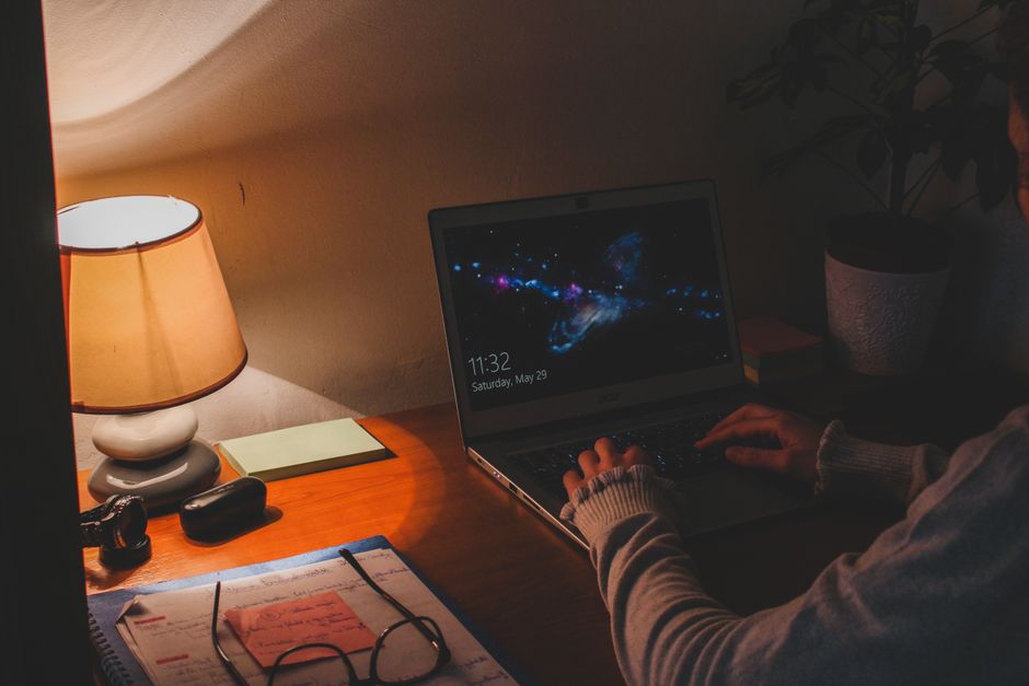 Person working at a laptop by warm lamplight at night